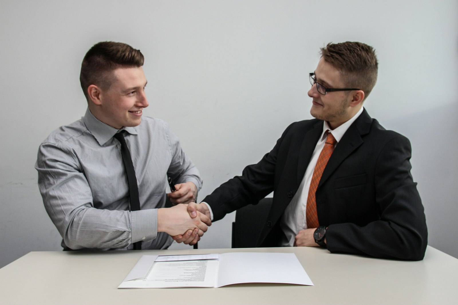 Professional handshake across a desk over a signed document