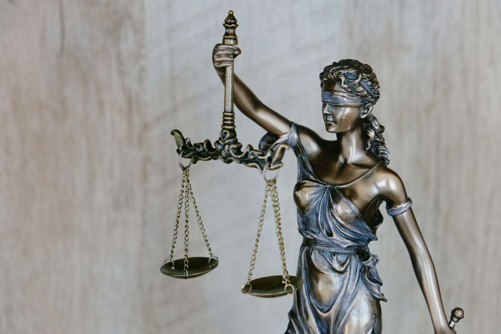 Warm bronze statue of Lady Justice holding balanced scales