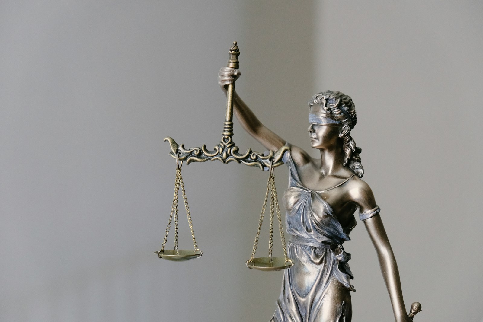 Bronze blindfolded Lady Justice statue holding balanced scales
